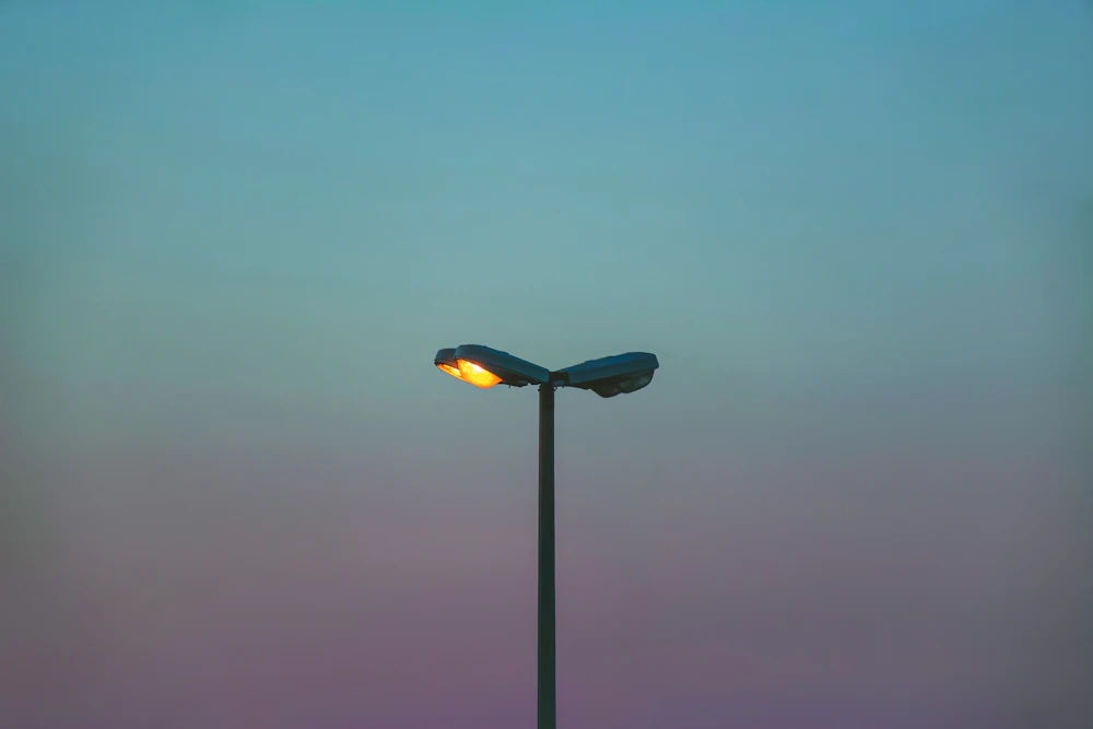 Twin-arm streetlight against a clear teal dusk sky